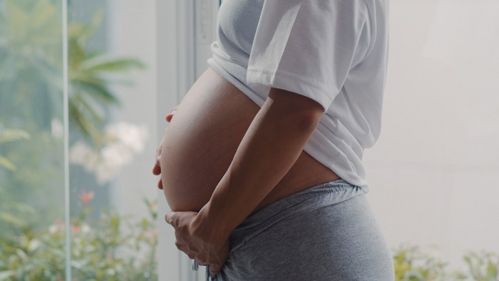 foto de uma mulher grávida em pé segurando a barriga